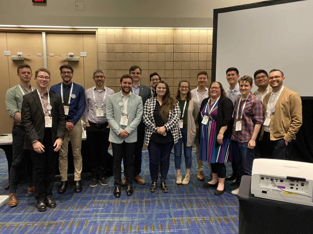 A group of presenters from the 2024 ACS Pride Merck Graduate Research Award symposium standing in the presentation room.