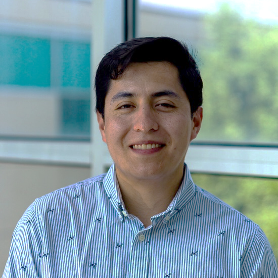 A person with black hair in a patterned white shirt smiling at the camera